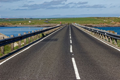 Road leading towards bridge against sky