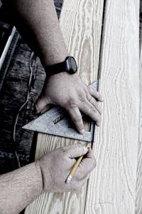 Hands of carpenter measuring plank at workshop