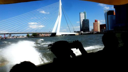 Silhouette bridge over sea against sky in city