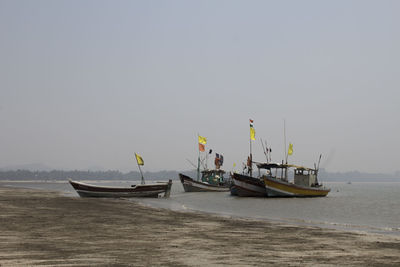 Fishing boats on sea against clear sky