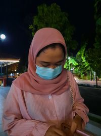 Midsection of woman wearing hat while standing at night