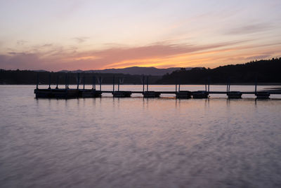 Silhouette of wooden posts in lake at sunset