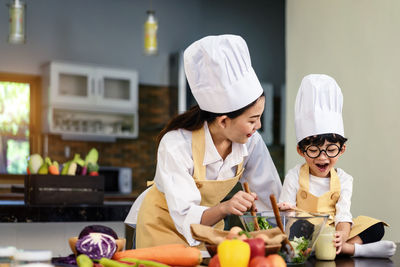 Mother with cute son preparing food in kitchen at home