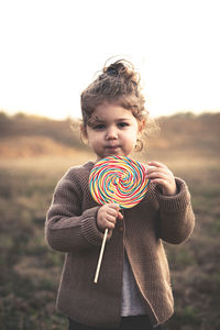 Portrait of cute girl with lollipop standing on field
