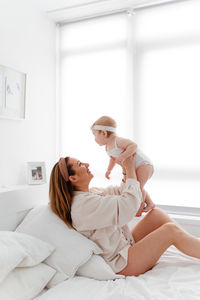 Woman sitting on bed at home