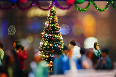 Tilt-shift image of illuminated christmas tree at party