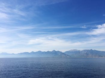 Scenic view of sea and mountains against blue sky