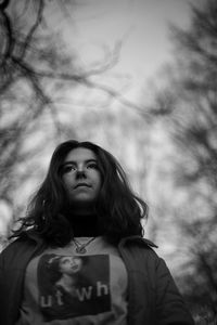 Beautiful young woman standing against trees