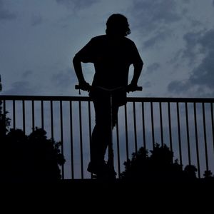 Silhouette man standing on bridge against sky at dusk