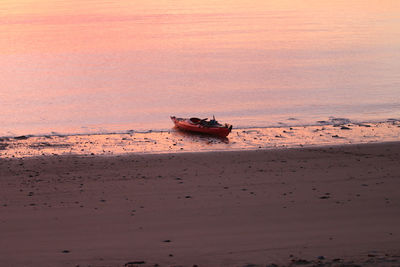 Boat on beach against sky during sunset