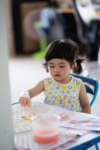 Full length of girl looking away while sitting on table