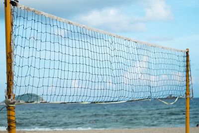 Close-up of net on beach against sky