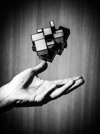 Close-up of hand holding cross against wall