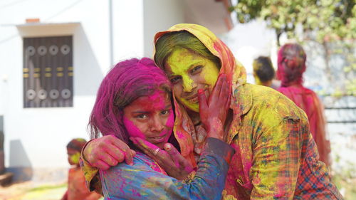 Outdoor image of asian, indian happy mother daughter in indian dress celebrating the holi festival 