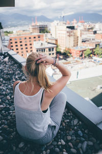 Woman photographing while sitting on retaining wall