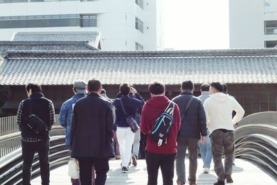 Rear view of people walking against buildings in city