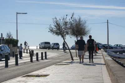 Rear view of people walking on street in city