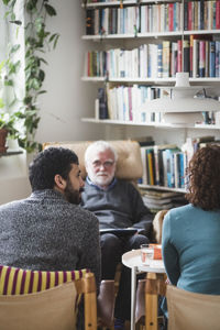 Mother and son sitting with senior therapist at home office