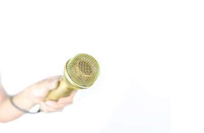 Close-up of hand holding ring over white background