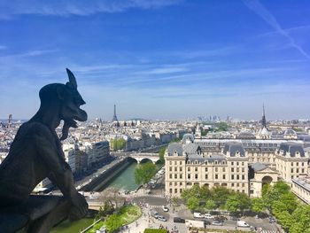 Statue in city against sky