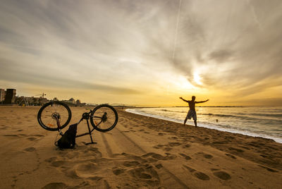 Man on beach against sky during sunset