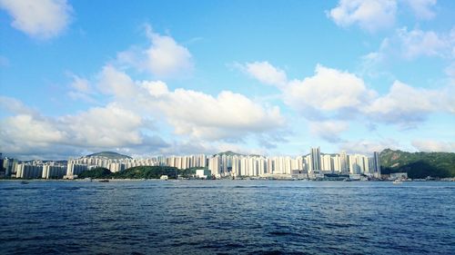 City at waterfront against cloudy sky