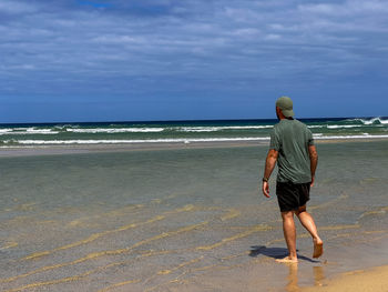 Full length of woman standing at beach against sky