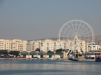 Ferris wheel by sea against clear sky