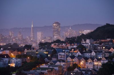 Illuminated cityscape against sky at dusk