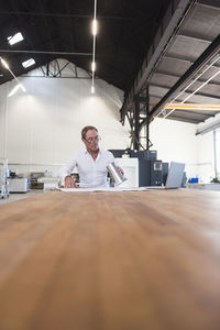 Man with plan, product and laptop on table in factory