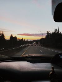 Road seen through car windshield during sunset