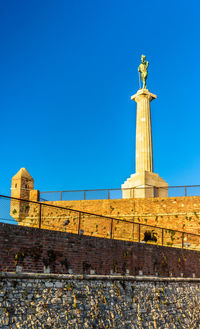 Low angle view of statue against blue sky