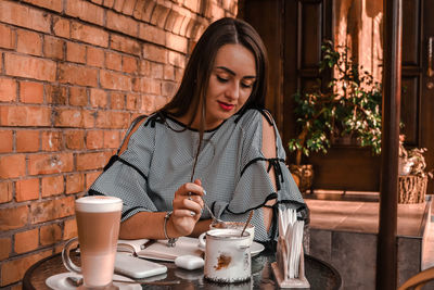 Young woman with coffee cup sitting on table