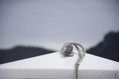 Close-up of rope tied on metal against sky