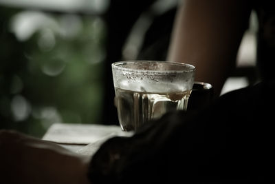 Close-up of hand holding drinking glass on table