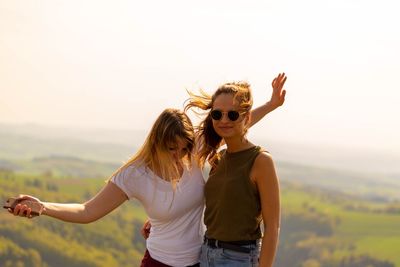 Portrait of smiling young woman standing by friends standing against sky