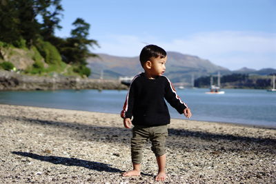 Side view of young man standing at beach