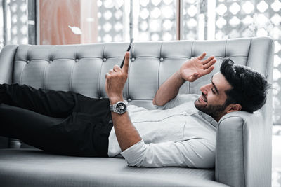 Young man using mobile phone while sitting on sofa