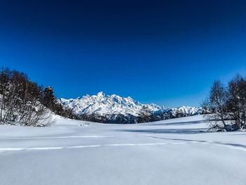 Snowcapped mountains against clear blue sky during winter