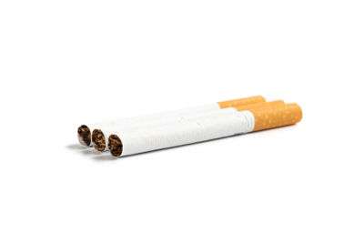 Close-up of cigarette on wood against white background