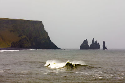 Scenic view of rocks in sea against clear sky
