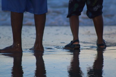 Low section of people standing on sea shore