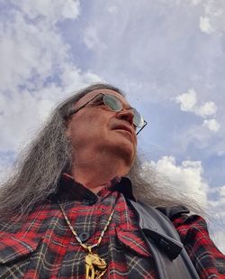 Low angle portrait of man wearing hat against sky