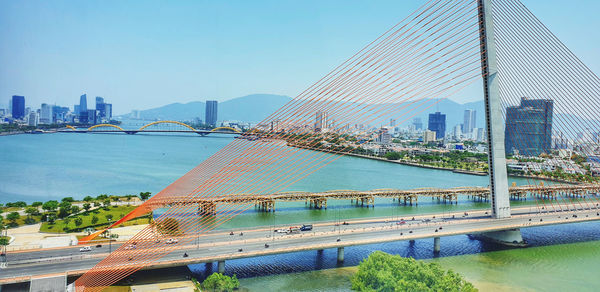 Suspension bridge over river with buildings in background