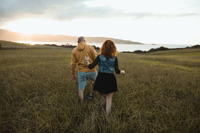 Rear view of friends walking on field