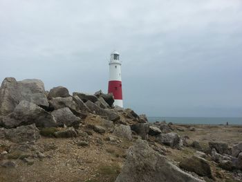 Lighthouse on beach against sky