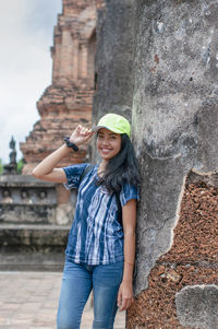 Portrait of happy young woman standing against built historical structure