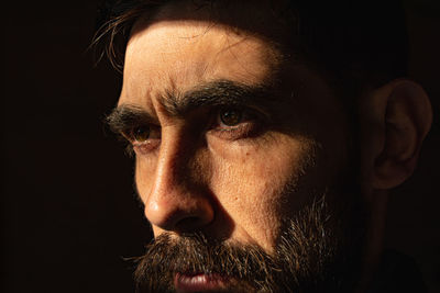 Man's face on black background behind a window with bars