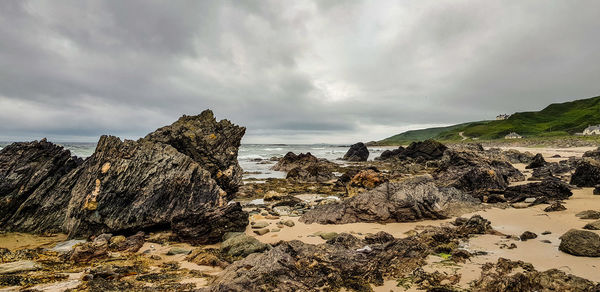 Rock formations on beach against sky