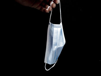 Midsection of person holding paper hanging against black background